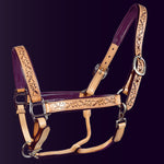 Full front view of the Wiskadero Halo and Horns padded leather halter. Highlights the tan saddle leather with deeply tooled halo, horn, and heart motifs, deep eggplant purple padded leather lining at the crown, noseband, and cheeks, and polished chrome hardware against a dark purple background.