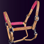 Full view of the Wiskadero Halo and Horns padded leather halter. Highlights the tan saddle leather with deeply tooled halo, horn, and heart motifs, vibrant raspberry/pink padded leather lining at the crown, noseband, and cheeks, and polished chrome hardware.